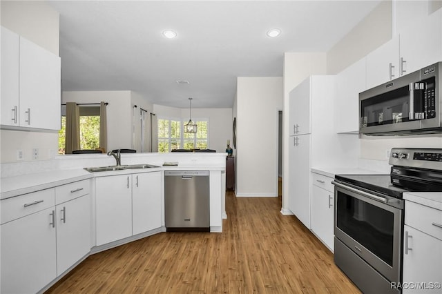 kitchen featuring a sink, stainless steel appliances, light countertops, white cabinets, and light wood-type flooring