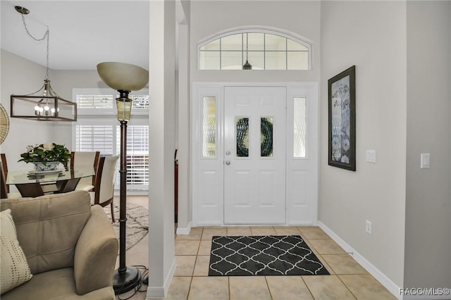 foyer entrance featuring a chandelier, light tile patterned floors, and baseboards