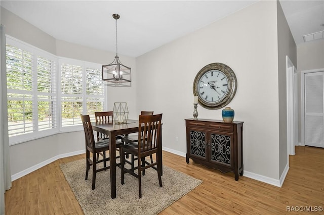 dining room with light wood finished floors, visible vents, a notable chandelier, and baseboards