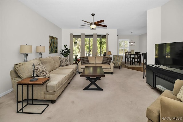 living area with light colored carpet, baseboards, and a ceiling fan