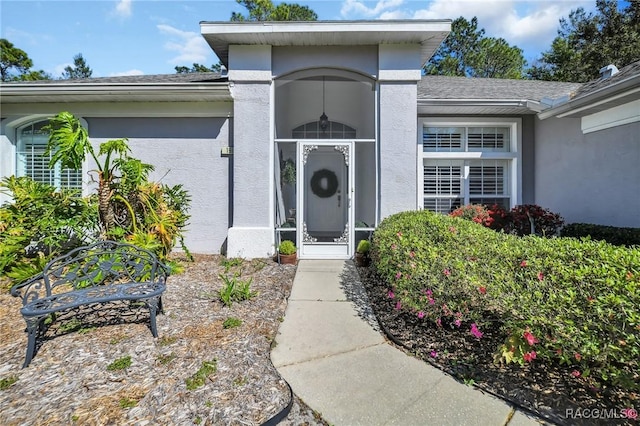 property entrance with a shingled roof and stucco siding