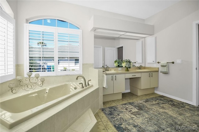 bathroom featuring tile patterned floors, a garden tub, a sink, double vanity, and baseboards