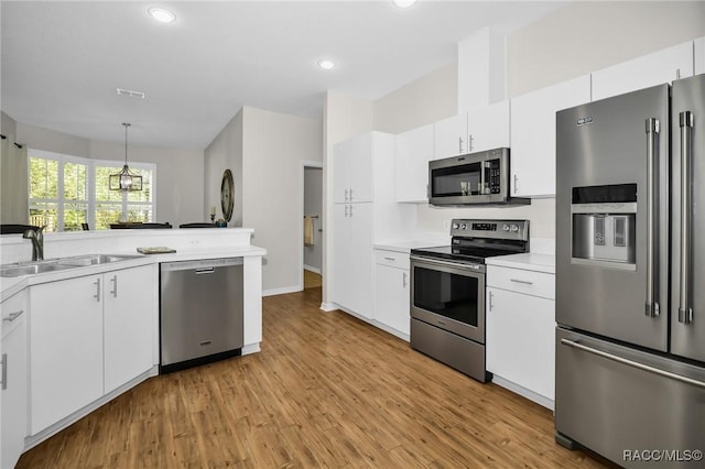 kitchen featuring light wood-style flooring, a sink, light countertops, white cabinets, and appliances with stainless steel finishes