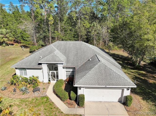 ranch-style home with roof with shingles, a garage, driveway, and stucco siding