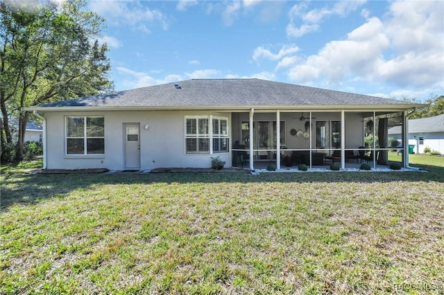 back of house with stucco siding, a lawn, roof with shingles, and a sunroom