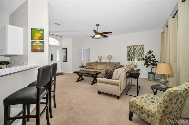 living room featuring visible vents, baseboards, light colored carpet, and a ceiling fan