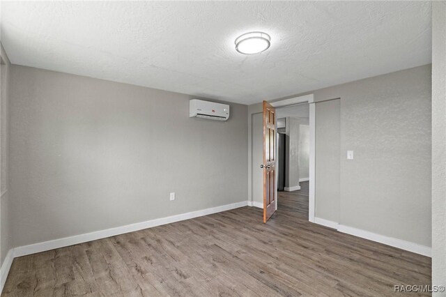 1 Taft St, Beverly Hills, FL 34465 - unfurnished bedroom featuring a wall mounted air conditioner, wood finished floors, baseboards, and a textured ceiling