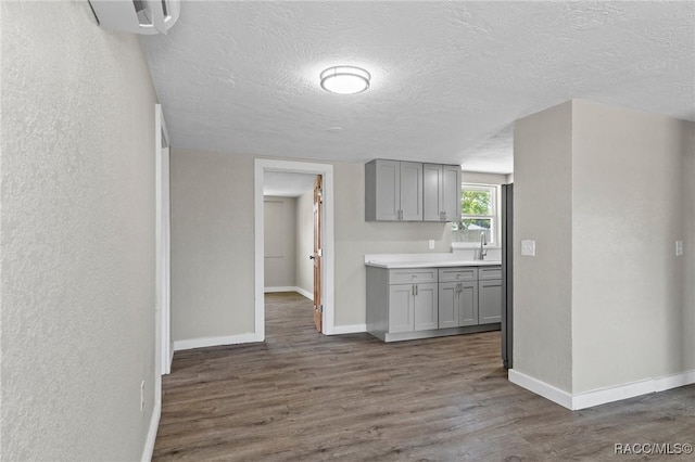 1 Taft St, Beverly Hills, FL 34465 - kitchen with gray cabinetry, a textured ceiling, dark wood-type flooring, a sink, and baseboards