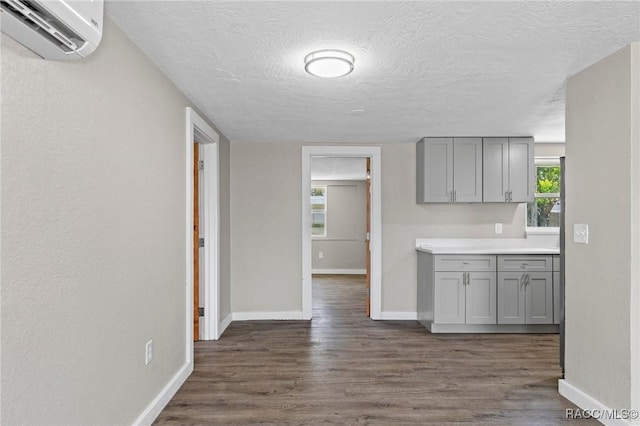 1 Taft St, Beverly Hills, FL 34465 - kitchen featuring gray cabinets, an AC wall unit, baseboards, dark wood-style flooring, and a textured ceiling