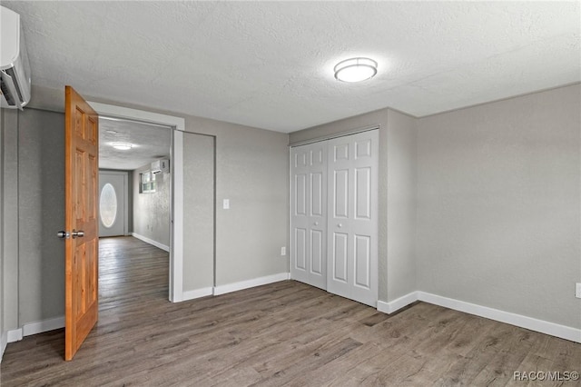 1 Taft St, Beverly Hills, FL 34465 - unfurnished bedroom featuring wood finished floors, baseboards, a textured ceiling, and a wall unit AC