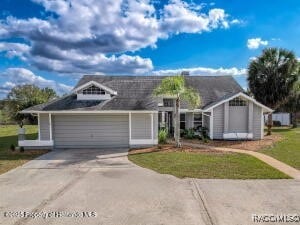 view of front facade with a garage, a front yard, and concrete driveway