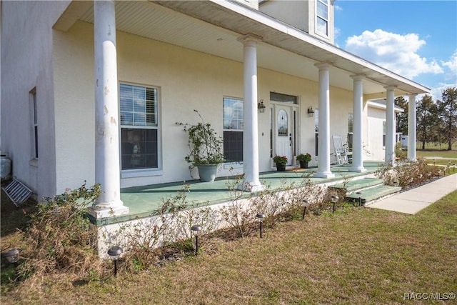 entrance to property featuring a yard and covered porch