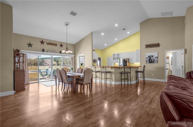 dining room featuring wood-type flooring, a notable chandelier, and high vaulted ceiling