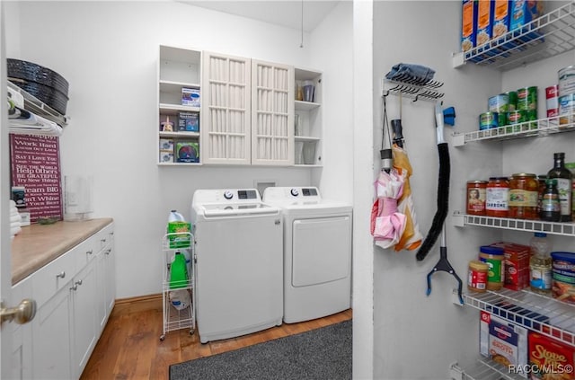 clothes washing area with washing machine and clothes dryer and light wood-type flooring