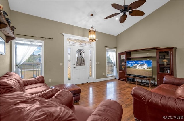 living room featuring ceiling fan with notable chandelier, hardwood / wood-style floors, and high vaulted ceiling