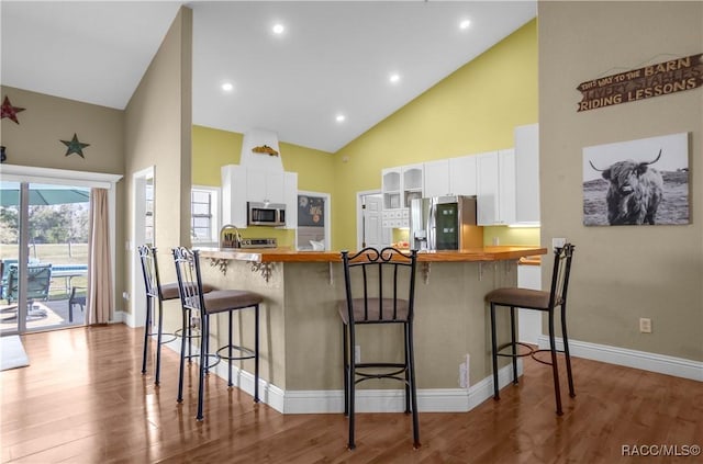 kitchen with white cabinetry, stainless steel appliances, kitchen peninsula, and a breakfast bar