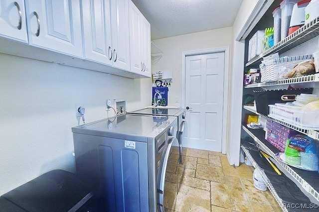 washroom featuring sink, cabinets, a textured ceiling, and independent washer and dryer