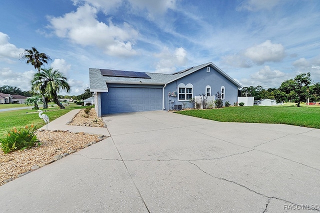 single story home featuring solar panels, a garage, and a front lawn