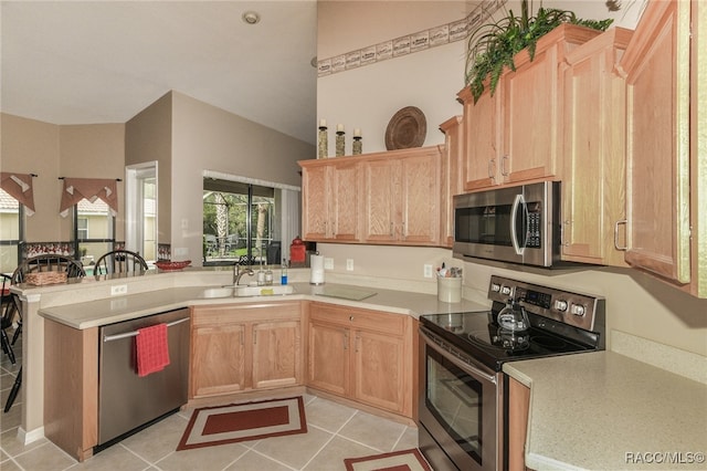 kitchen featuring sink, stainless steel appliances, kitchen peninsula, light brown cabinetry, and light tile patterned floors