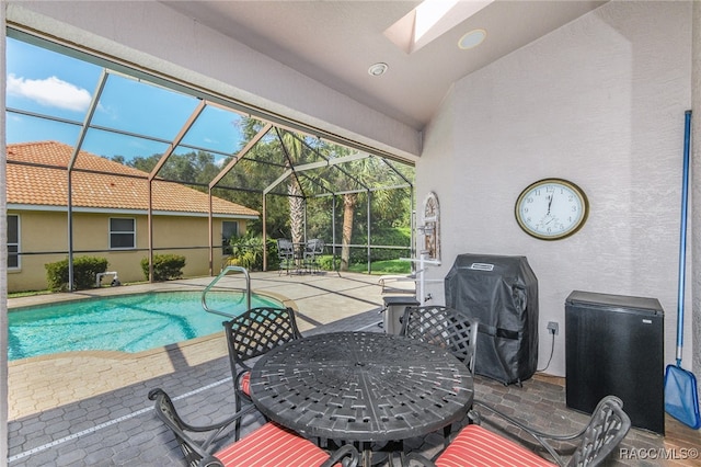 view of swimming pool with glass enclosure, a patio, and grilling area