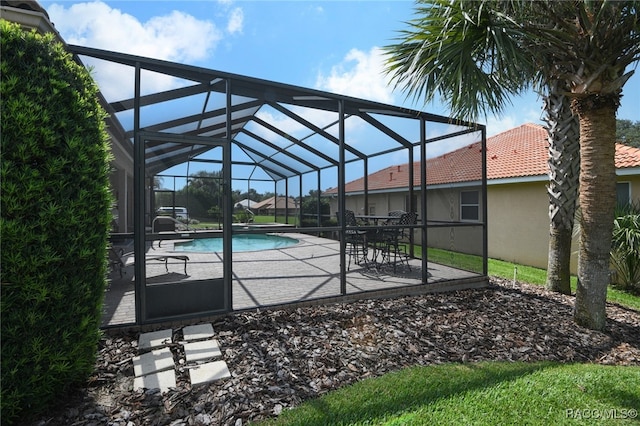 view of swimming pool with glass enclosure and a patio