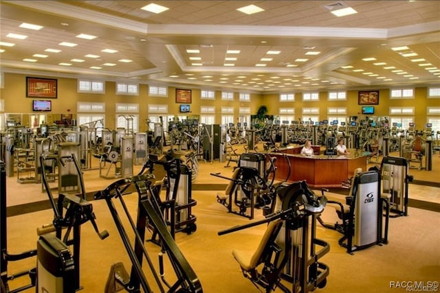 gym featuring ornamental molding, light carpet, and coffered ceiling