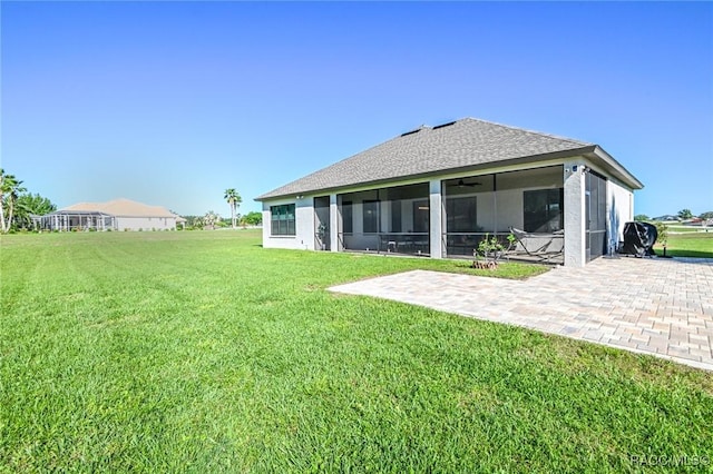 back of property with a sunroom, a patio area, and a lawn