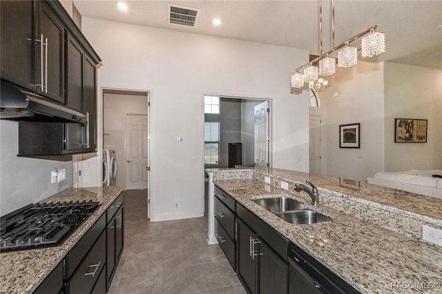 kitchen featuring black gas cooktop, sink, light stone countertops, separate washer and dryer, and dark brown cabinets