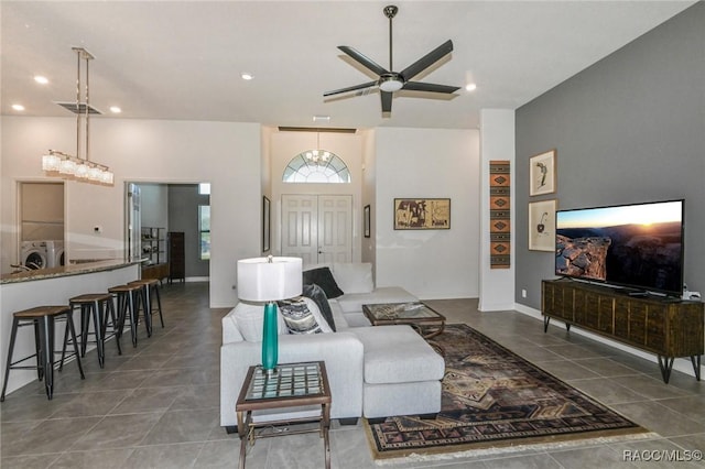 living room featuring ceiling fan, dark tile patterned floors, a towering ceiling, and washing machine and clothes dryer