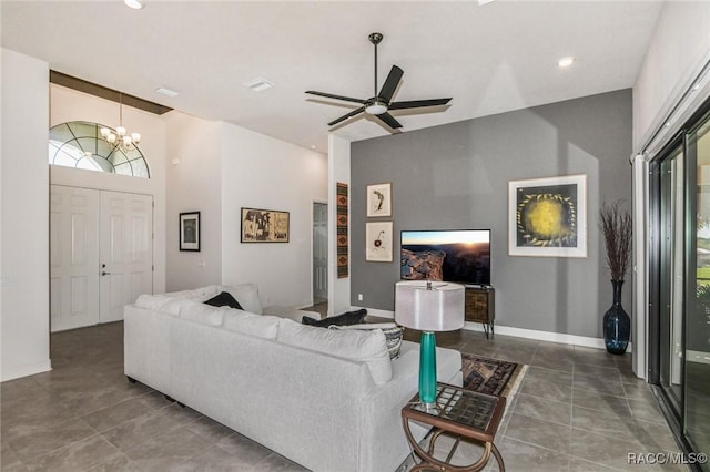 tiled living room featuring a high ceiling and ceiling fan with notable chandelier