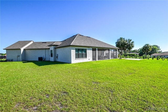 rear view of house with a sunroom, central AC, and a lawn