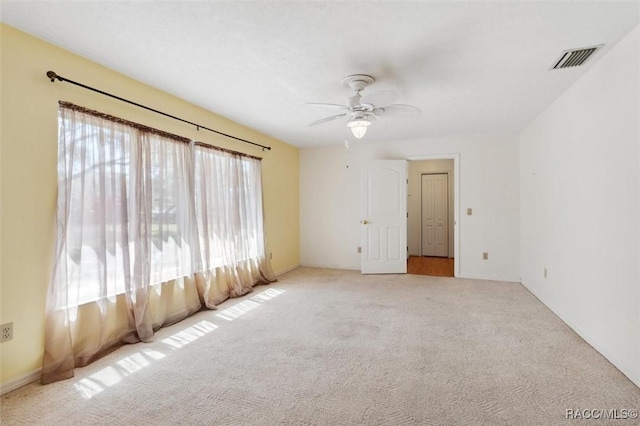 empty room with a ceiling fan, visible vents, and carpet flooring