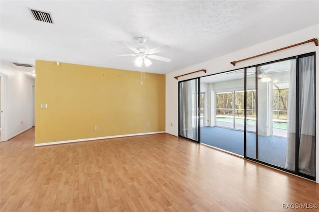 empty room with light wood finished floors, visible vents, baseboards, ceiling fan, and a textured ceiling