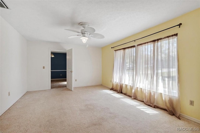 carpeted empty room featuring a ceiling fan and visible vents