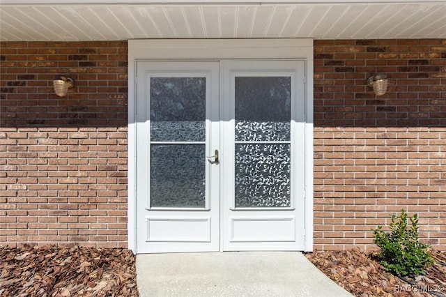 view of exterior entry featuring brick siding and french doors