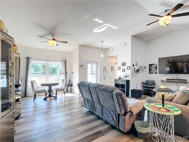 living room with hardwood / wood-style floors, a textured ceiling, vaulted ceiling, and ceiling fan