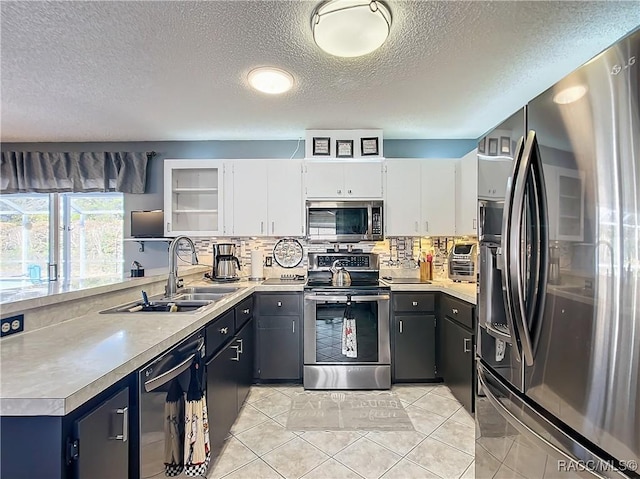 kitchen with sink, light tile patterned floors, backsplash, stainless steel appliances, and white cabinets