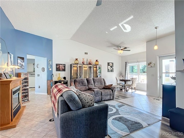 living room featuring lofted ceiling, a textured ceiling, ceiling fan, and light tile patterned flooring