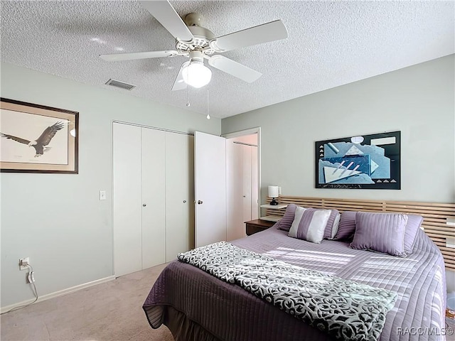 bedroom featuring ceiling fan, light carpet, a textured ceiling, and a closet