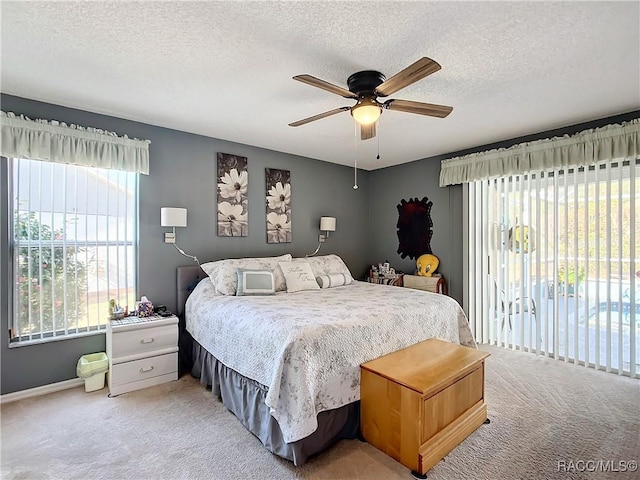 carpeted bedroom featuring ceiling fan and a textured ceiling