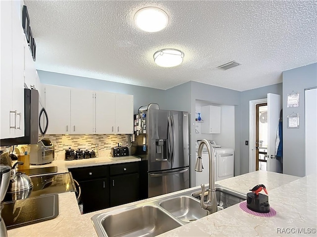 kitchen featuring white cabinetry, a textured ceiling, washer and dryer, stainless steel appliances, and decorative backsplash