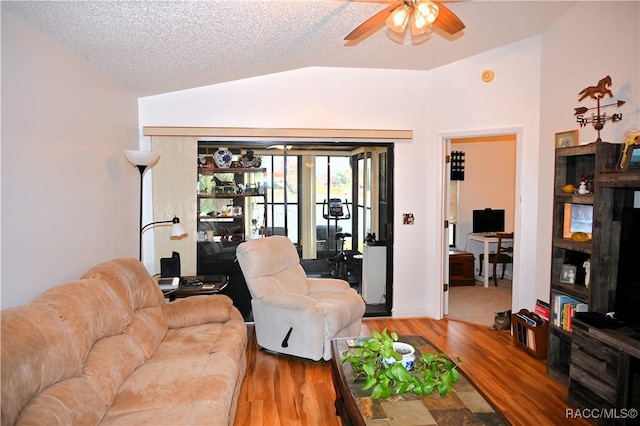 living room with ceiling fan, vaulted ceiling, a textured ceiling, and hardwood / wood-style flooring