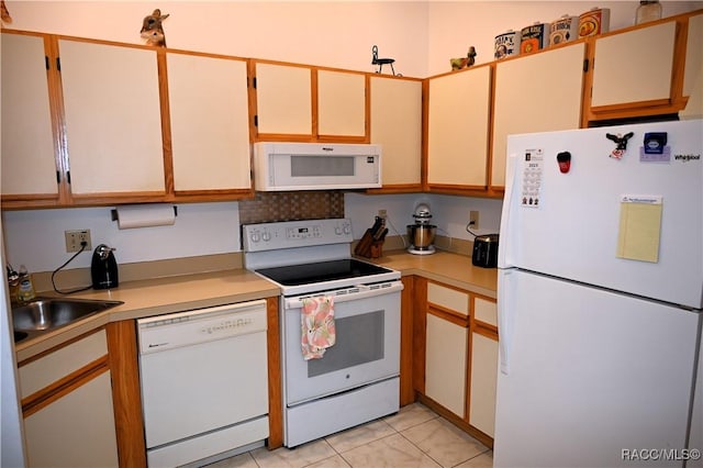 kitchen with white appliances, light tile patterned floors, and sink