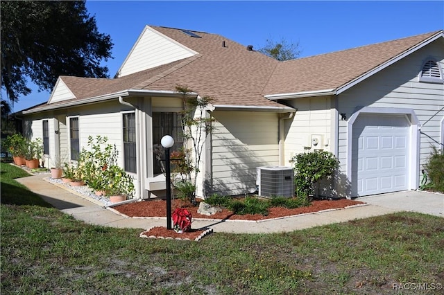 view of front of house featuring a garage, cooling unit, and a front lawn