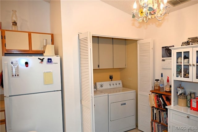 laundry area featuring a notable chandelier, cabinets, and washing machine and clothes dryer