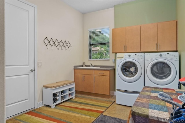 laundry room featuring sink, washing machine and clothes dryer, and cabinets