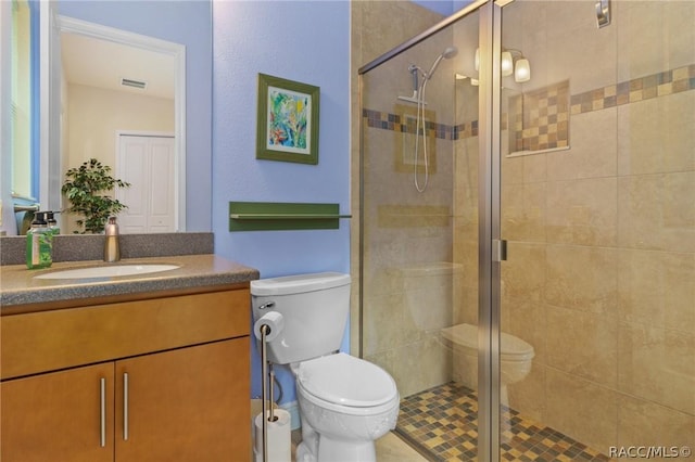 bathroom with toilet, a shower with shower door, and vanity