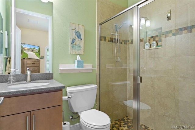 bathroom featuring toilet, a shower with shower door, and vanity