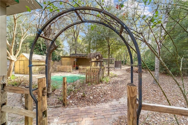 view of yard featuring a storage unit, fence, an outbuilding, and an outdoor pool