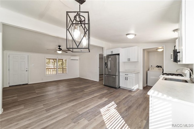 kitchen with white cabinets, washer / dryer, decorative light fixtures, stainless steel fridge with ice dispenser, and a sink